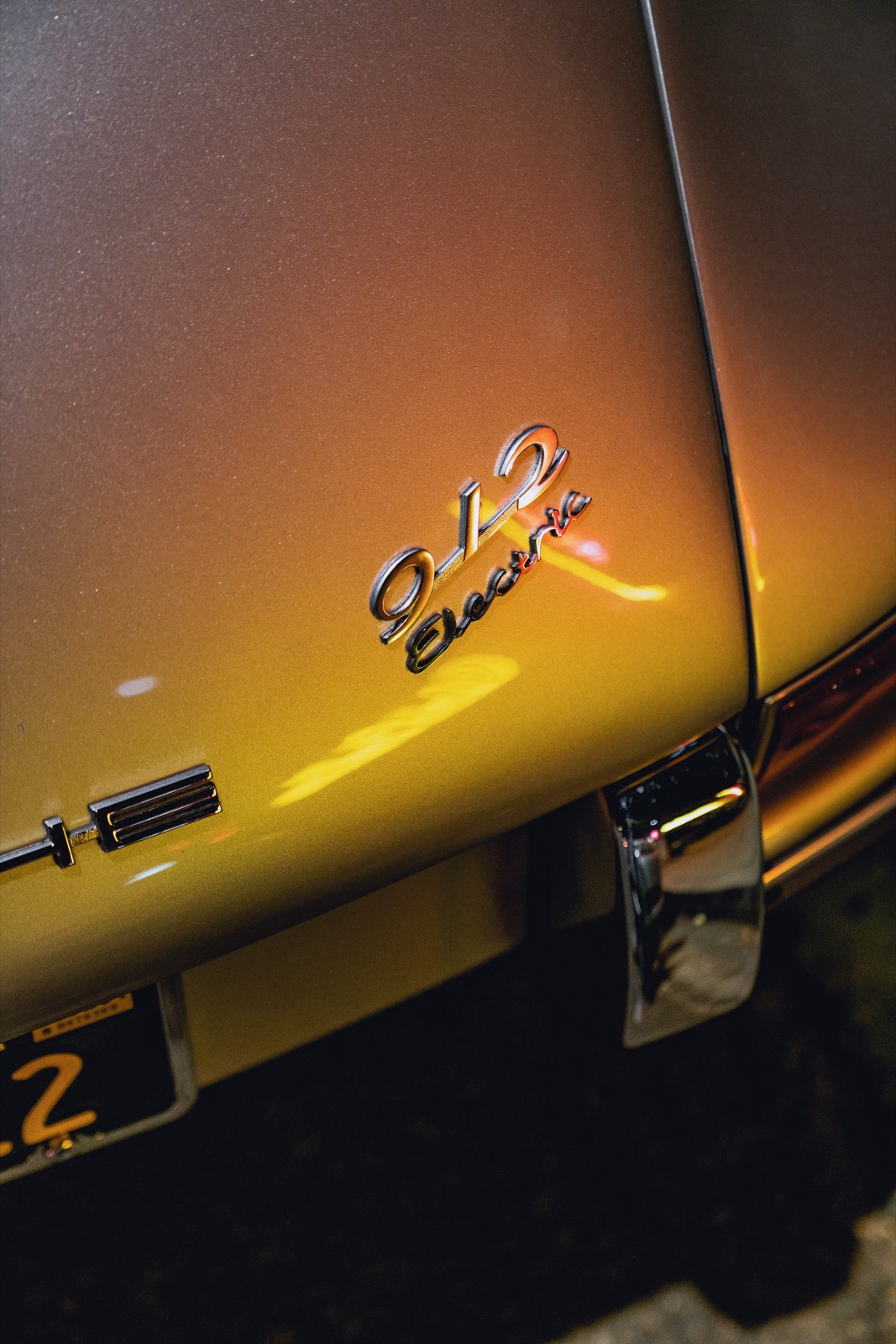 The ‘912 Electric’ rear badge glowing gold at night